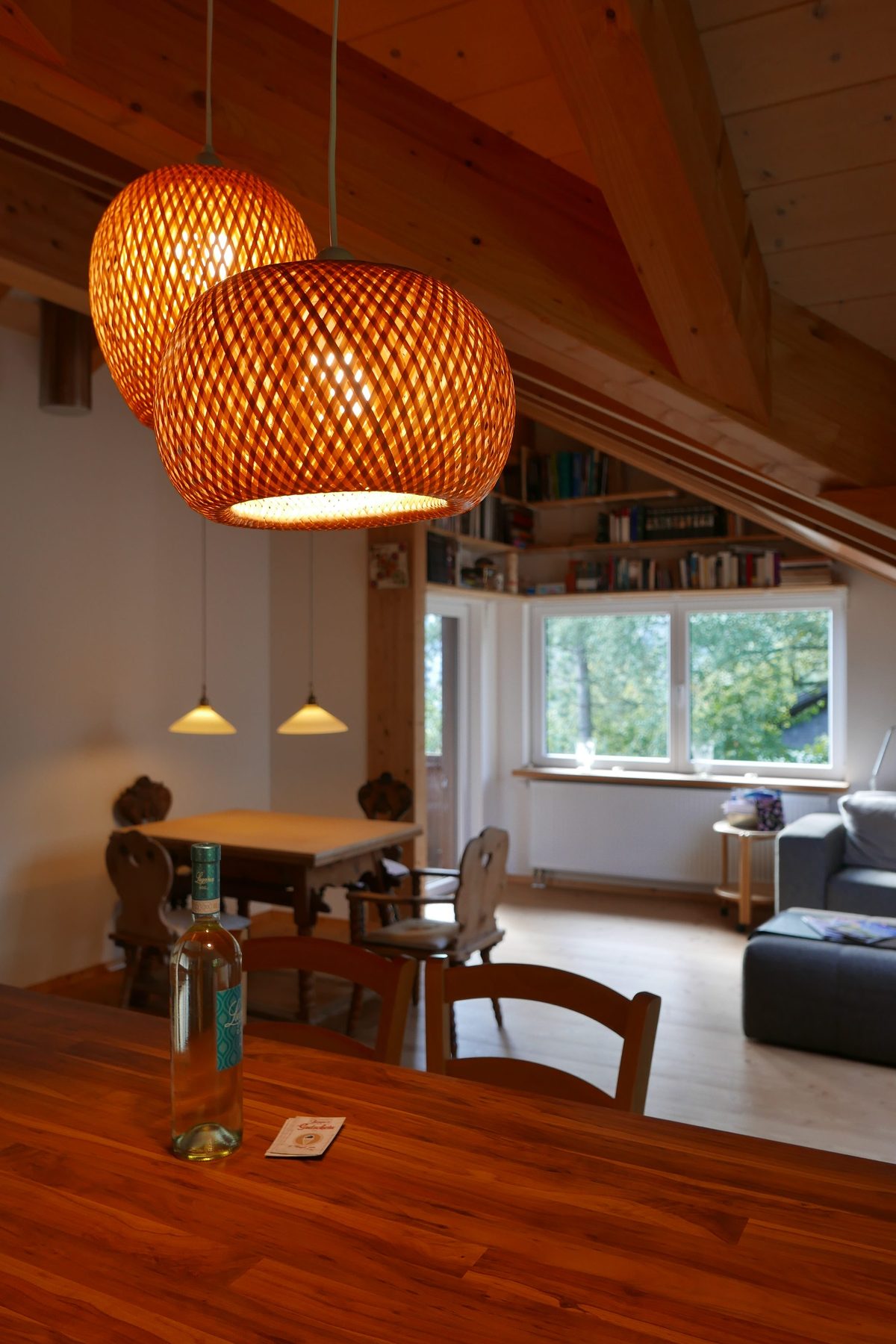 Theke aus dunklem Holz mit Hängeleuchten, Blick zum Wohnbereich