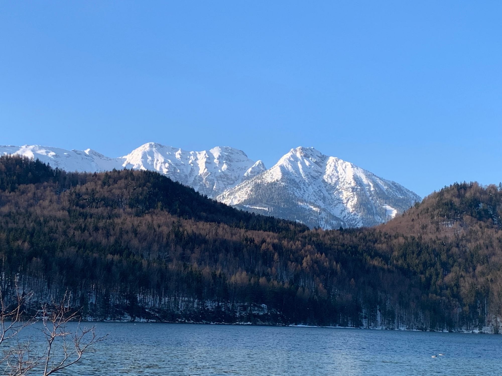 Weißensee im Winter mit verschneiten Gipfeln unter blauem Himmel